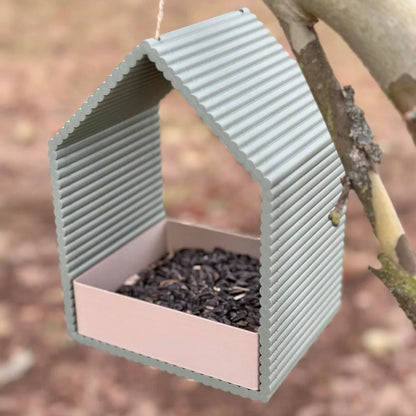 Bird feeder hanging from a branch with blurred natural background