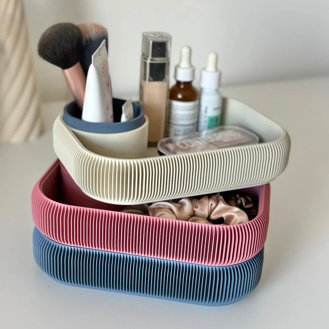 Stack of three colorful storage baskets with cosmetic items on a white surface